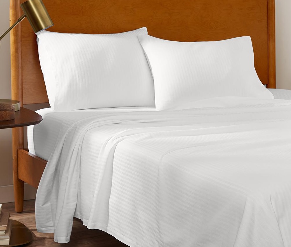 a bed featuring a white striped Comfortwil sheet set