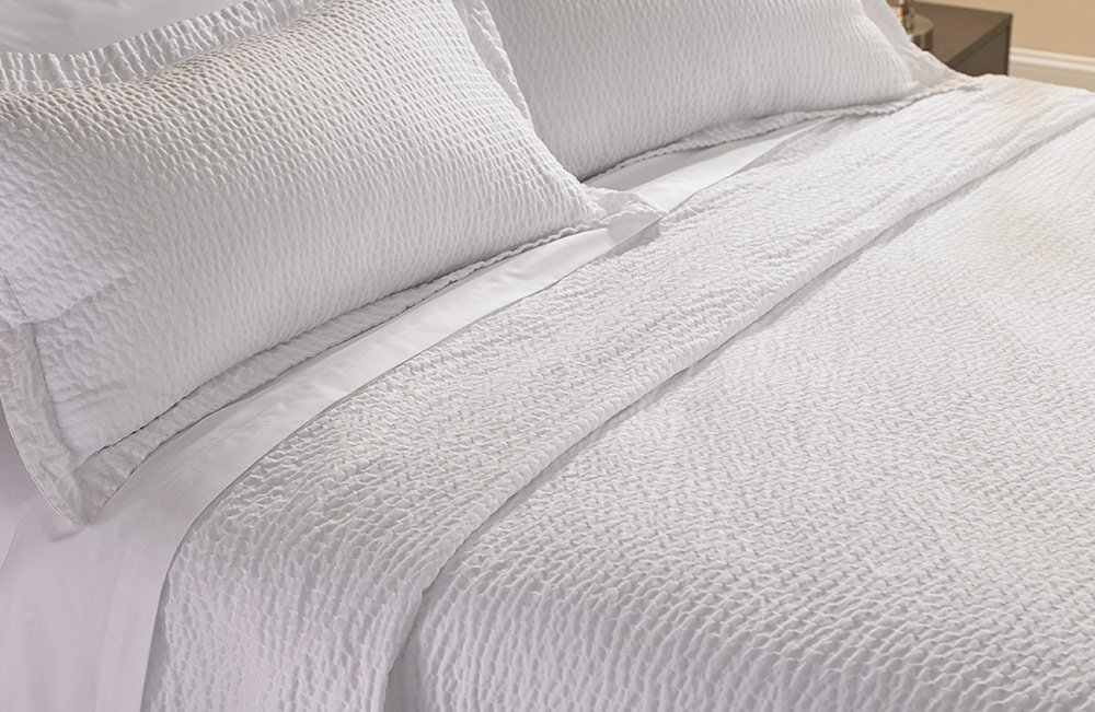 a bed with white sheets and a Cumulus top cover