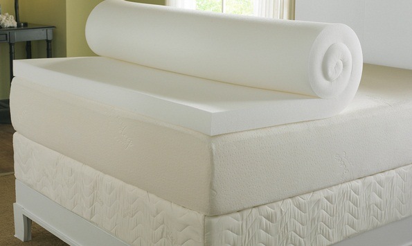 a rolled up mattress topper on a bed