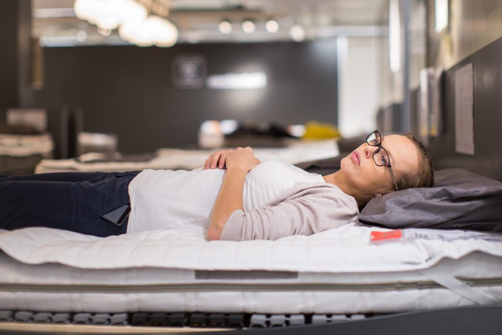 a woman laying on a mattress in a store