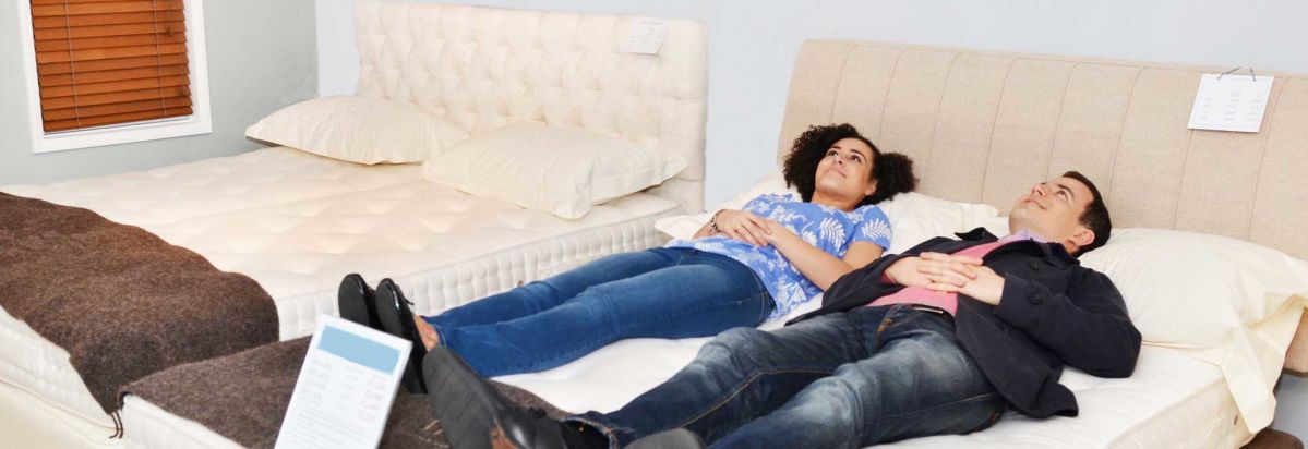 a couple laying on a mattress in a store