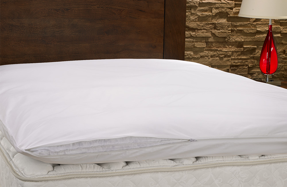 a featherbed encased in a featherbed protector, laying on top of a mattress.