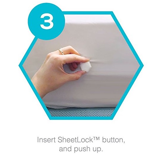 buttoning the Sheetlock into place on the fitted sheet