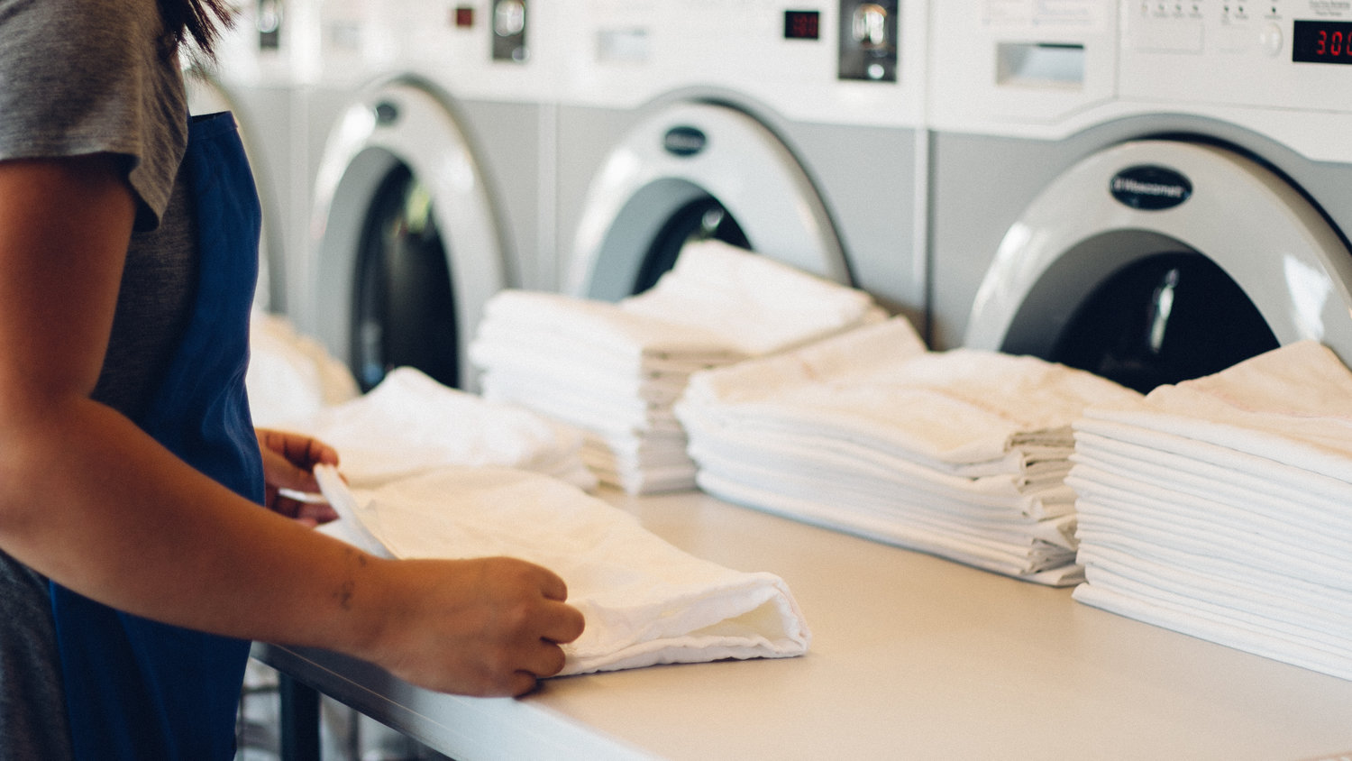 a woman folding sheets in a laundry facility
