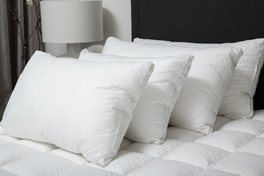 four firm pillows lined up on a hotel bed