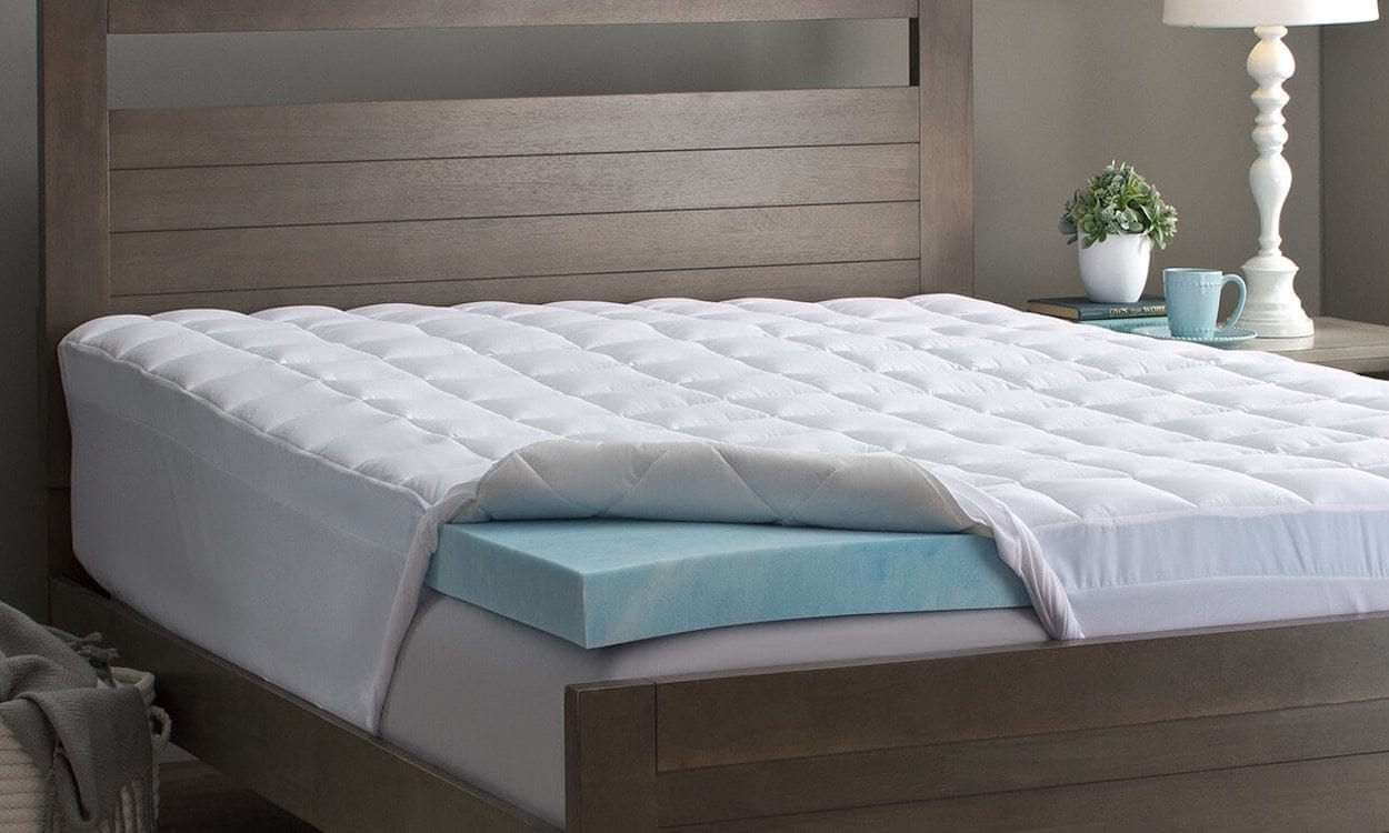 a mattress topper placed under a mattress pad on the bed