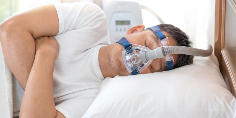 a man sleeping in bed with a CPAP mask