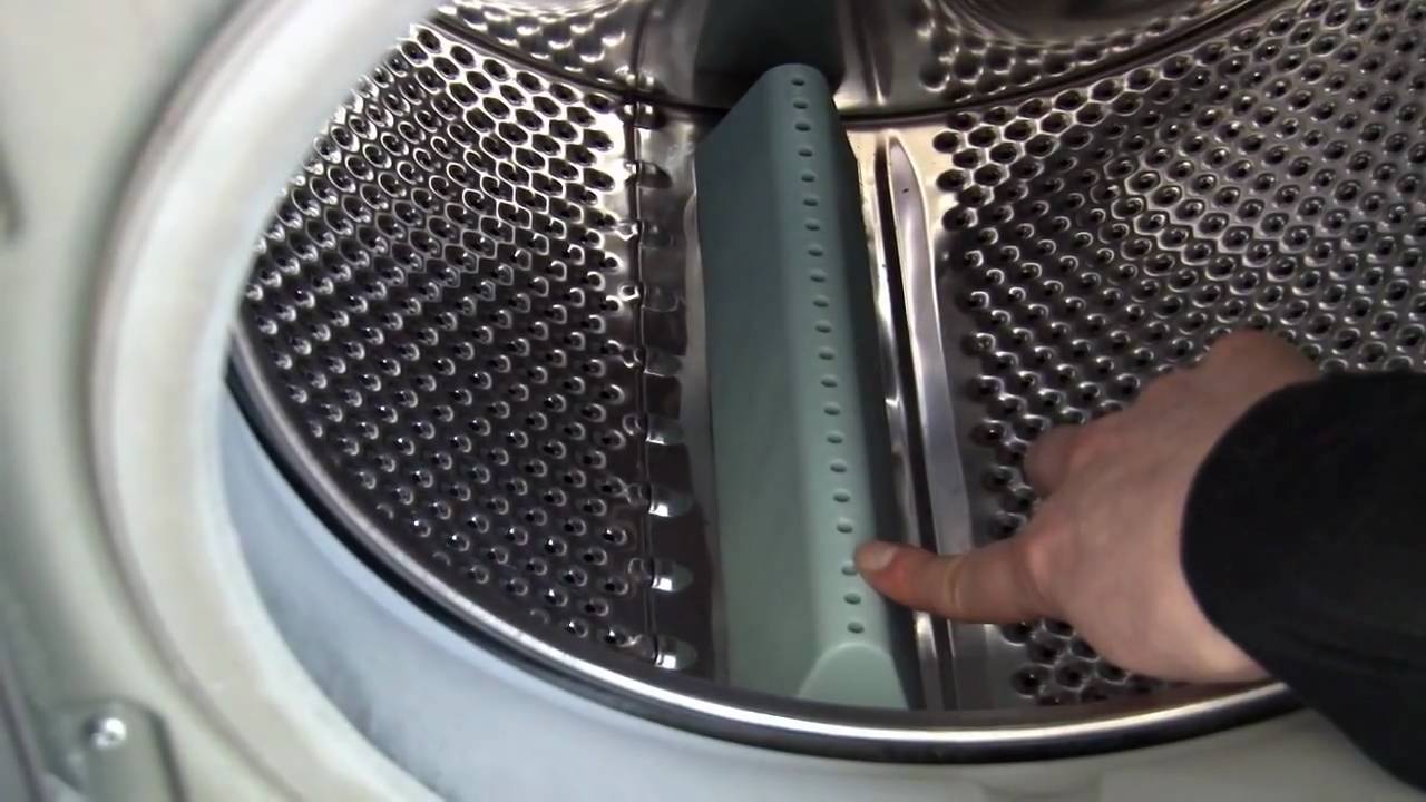 a woman pointing to the paddles inside of a washing machine