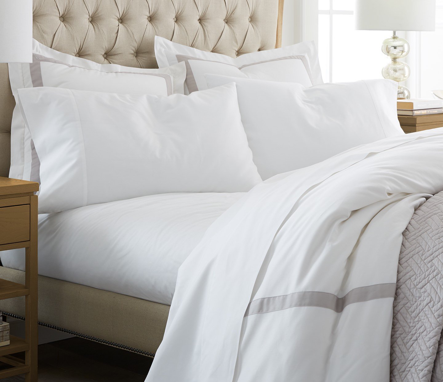 a bed with white sheets and duvet cover
