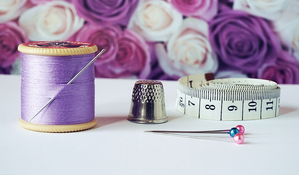 a sewing kit - thread, thimble, needles, and measuring tape