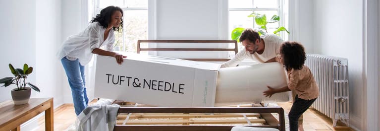 3 people taking a Tuft & Needle mattress out of the box