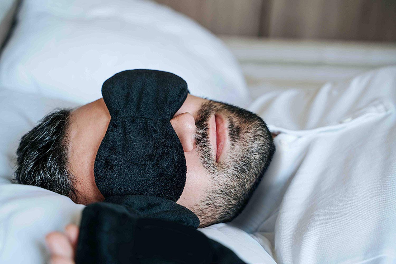 a man asleep in bed and wearing a weighted sleep mask