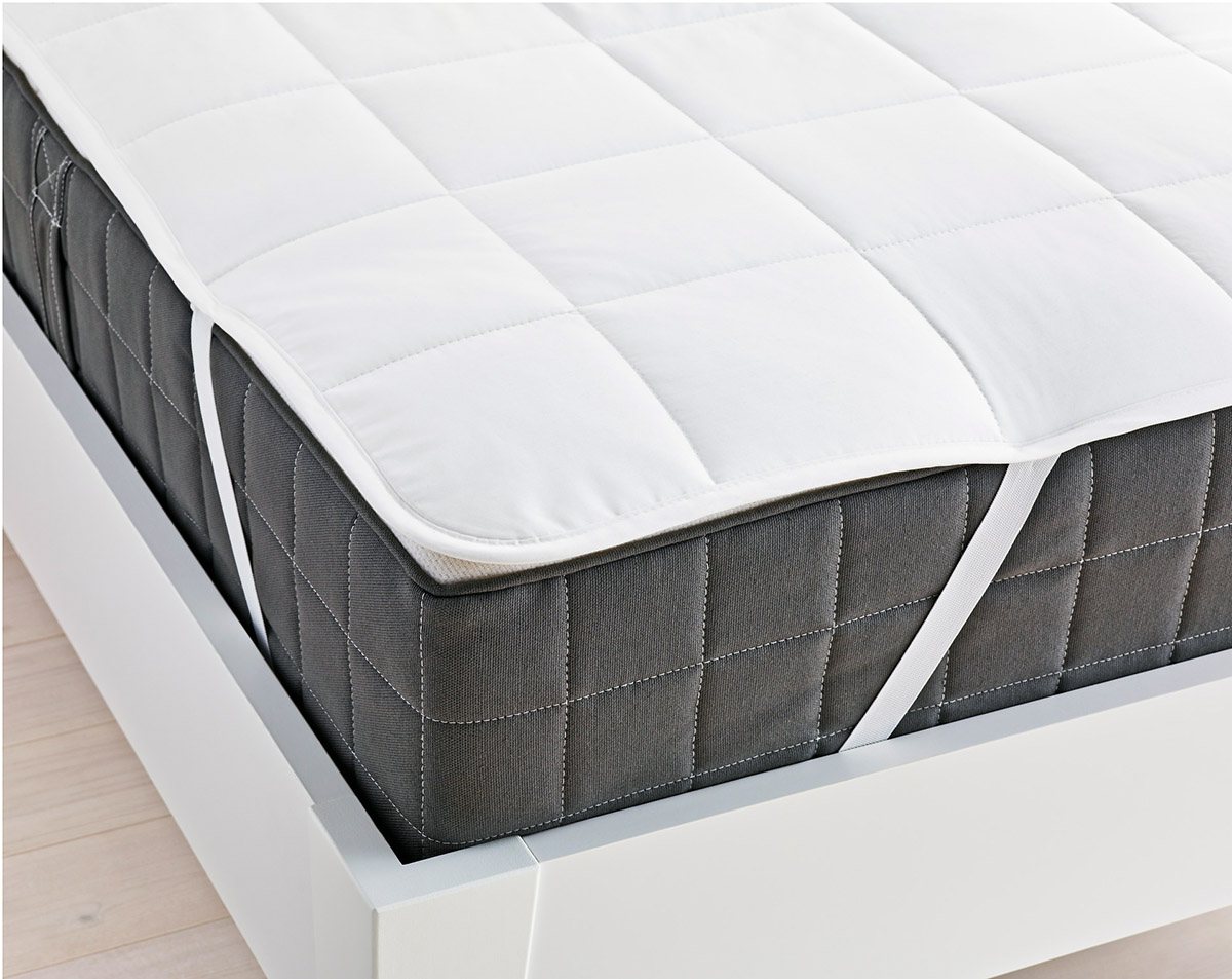 a white mattress pad with anchor bands placed on a mattress