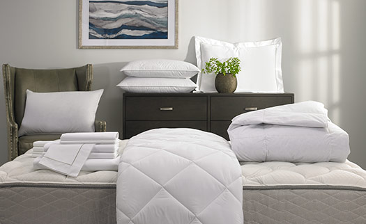 various bedding and linen items folded and arranged in a bedroom