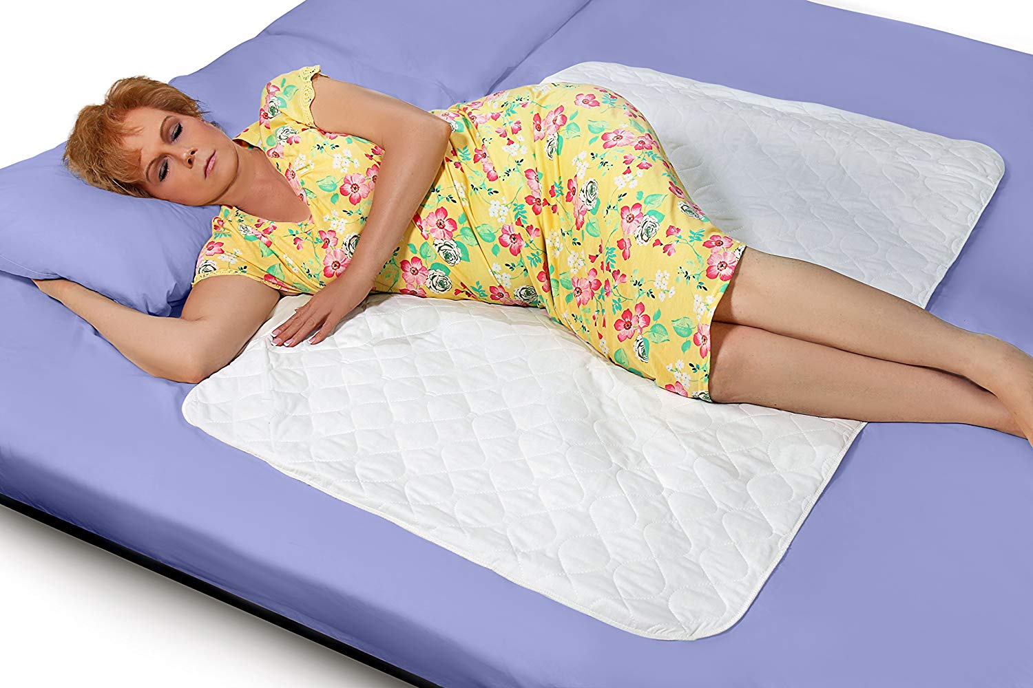 a woman laying on an incontinence pad in bed
