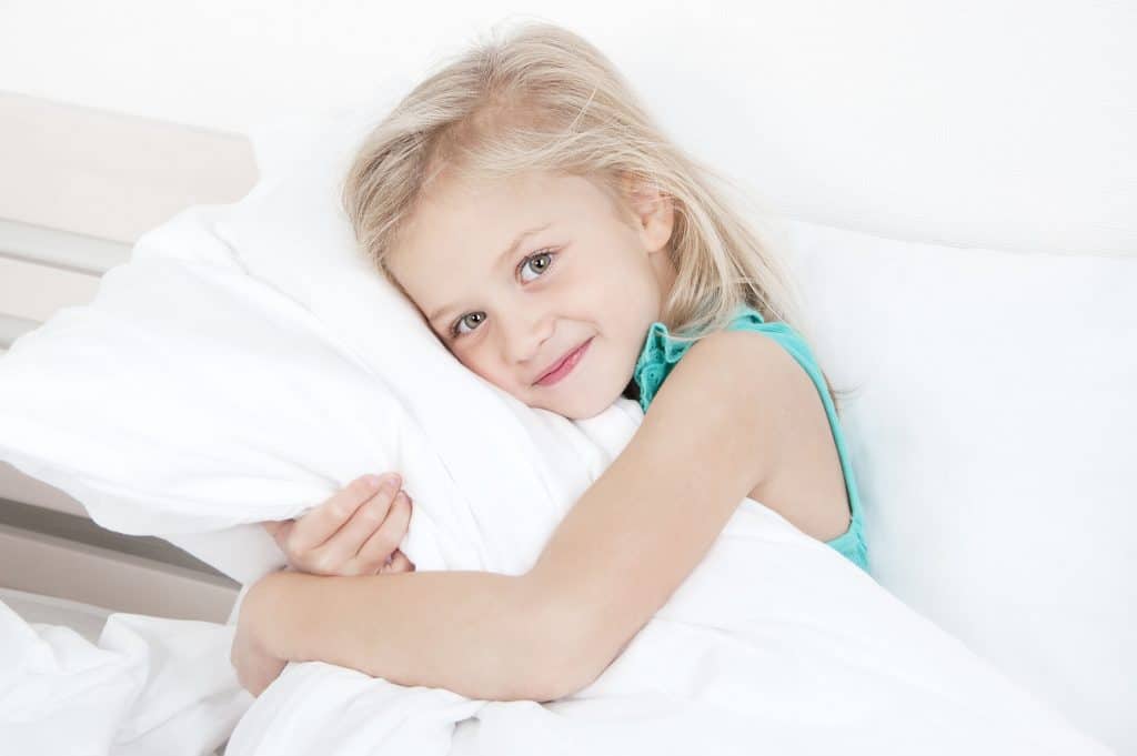 a young girl hugging a pillow