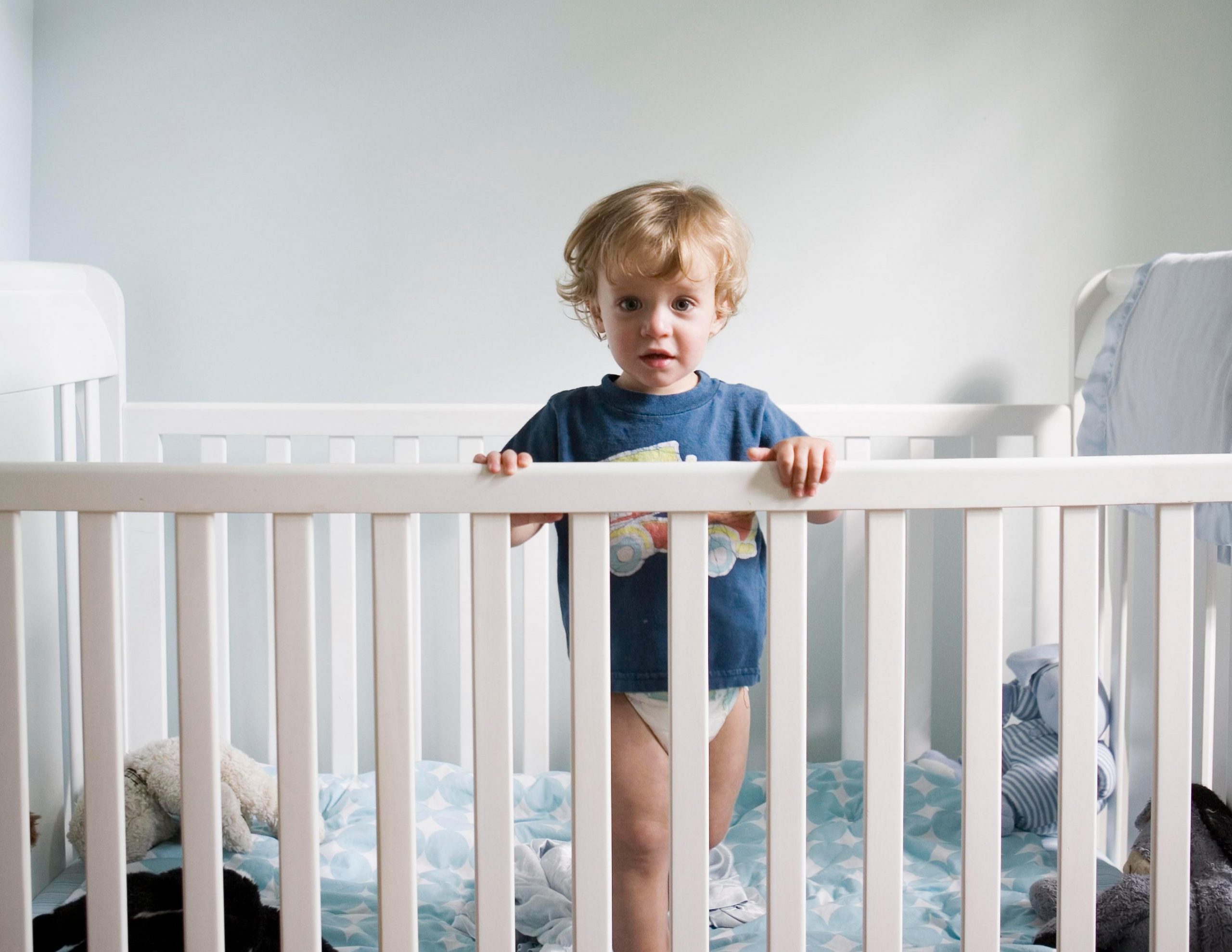 a toddler standing in a crib