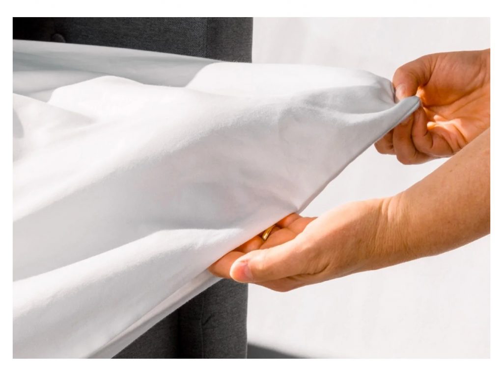 a person reaching into the hidden vent on a white QuickZip duvet cover